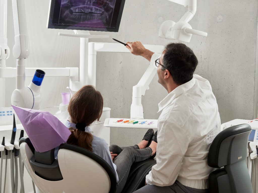 Dentista explicando diagnóstico para paciente em consultório odontológico